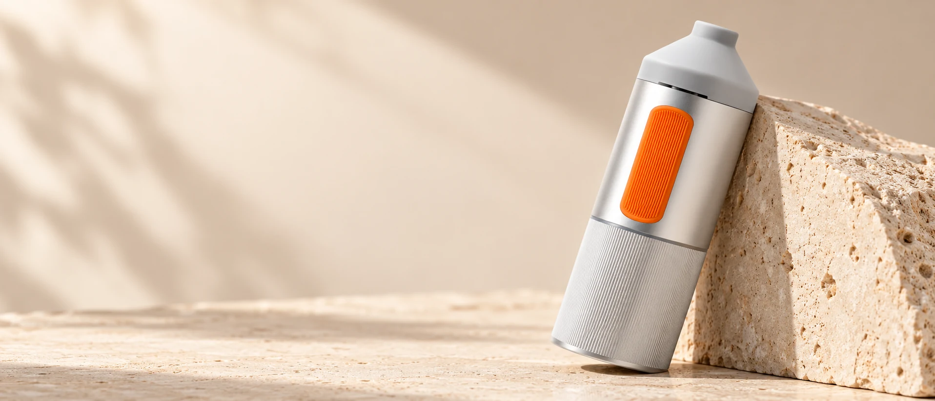 Silver SparkIt TRI orange silicone grip and CNC-ribbed aluminum against natural stone